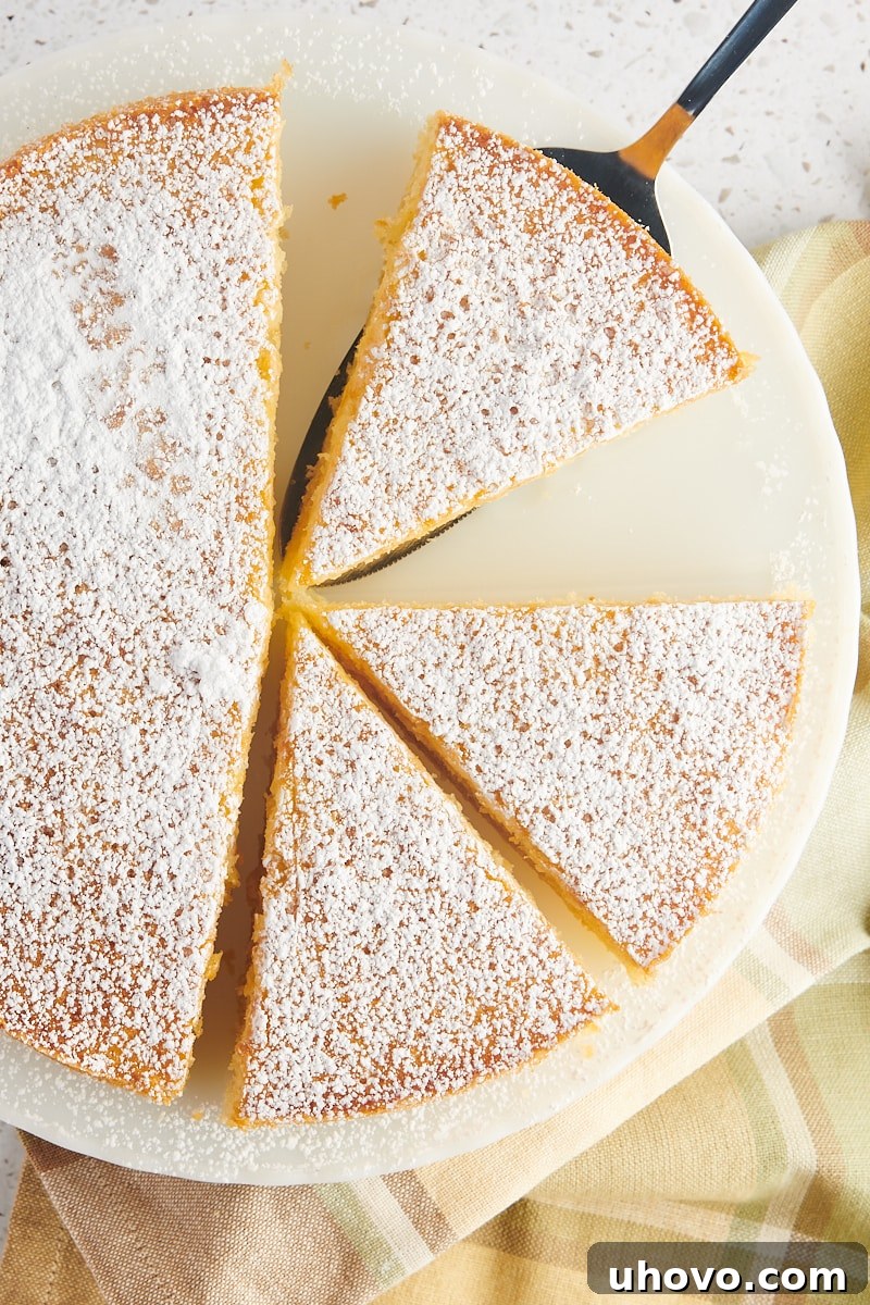 overhead view of partially sliced olive oil cake on a white cake stand