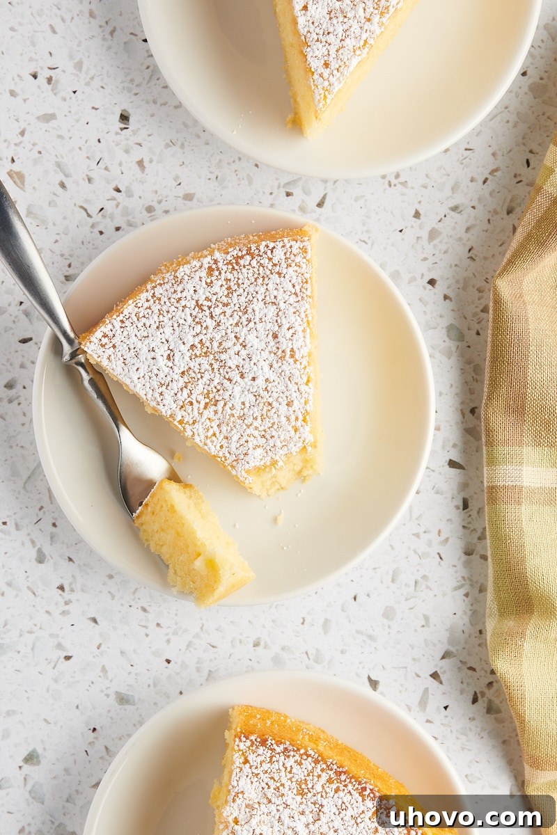 overhead view of a slice of olive oil cake on a white plate with a bite on a fork