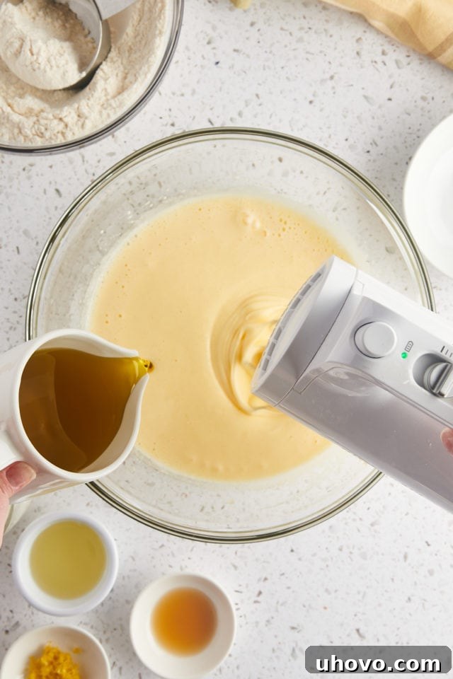 overhead view of olive oil being added to cake batter