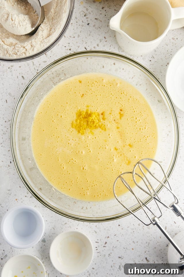 overhead view of milk, lemon zest, lemon juice, and vanilla extract added to olive oil cake batter
