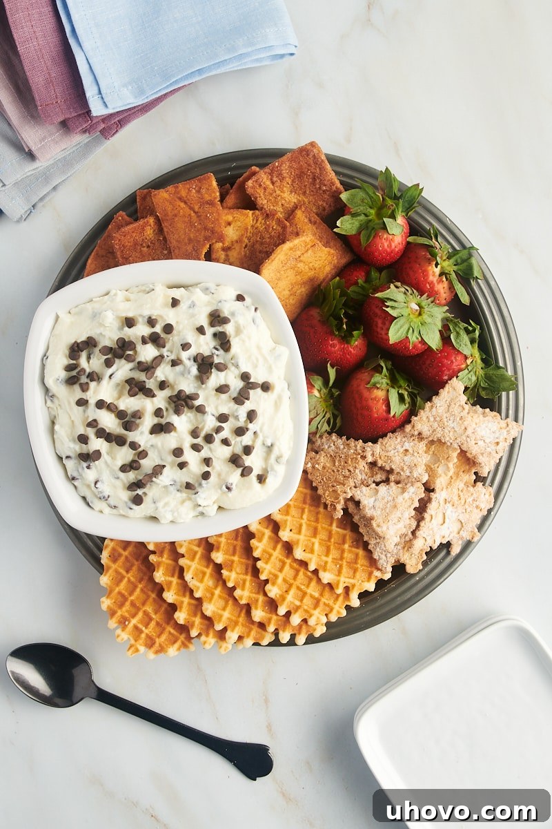 overhead view of cannoli dip in a white bowl along with various dippers on a pewter tray