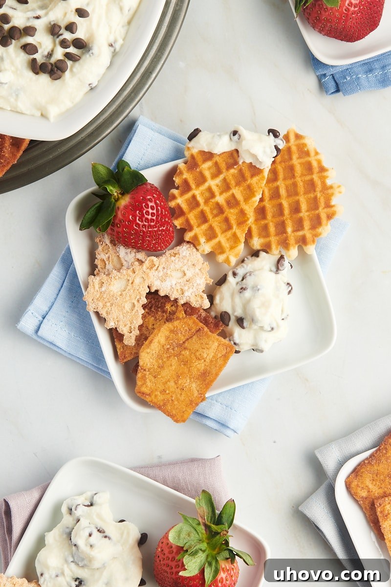 cannoli dip served on a square white plate with waffle cookies, strawberry, and pita chips; more plates surrounding