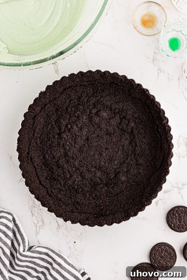 An overhead view of the baked and completely cooled Oreo cookie crust nestled in a tart pan, ready for its delicious filling.