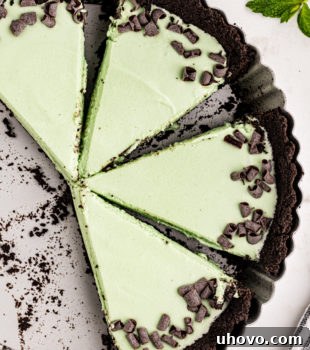 Four slices of Grasshopper Pie arranged perfectly in a metal tart pan, highlighting the green filling and chocolate crust.