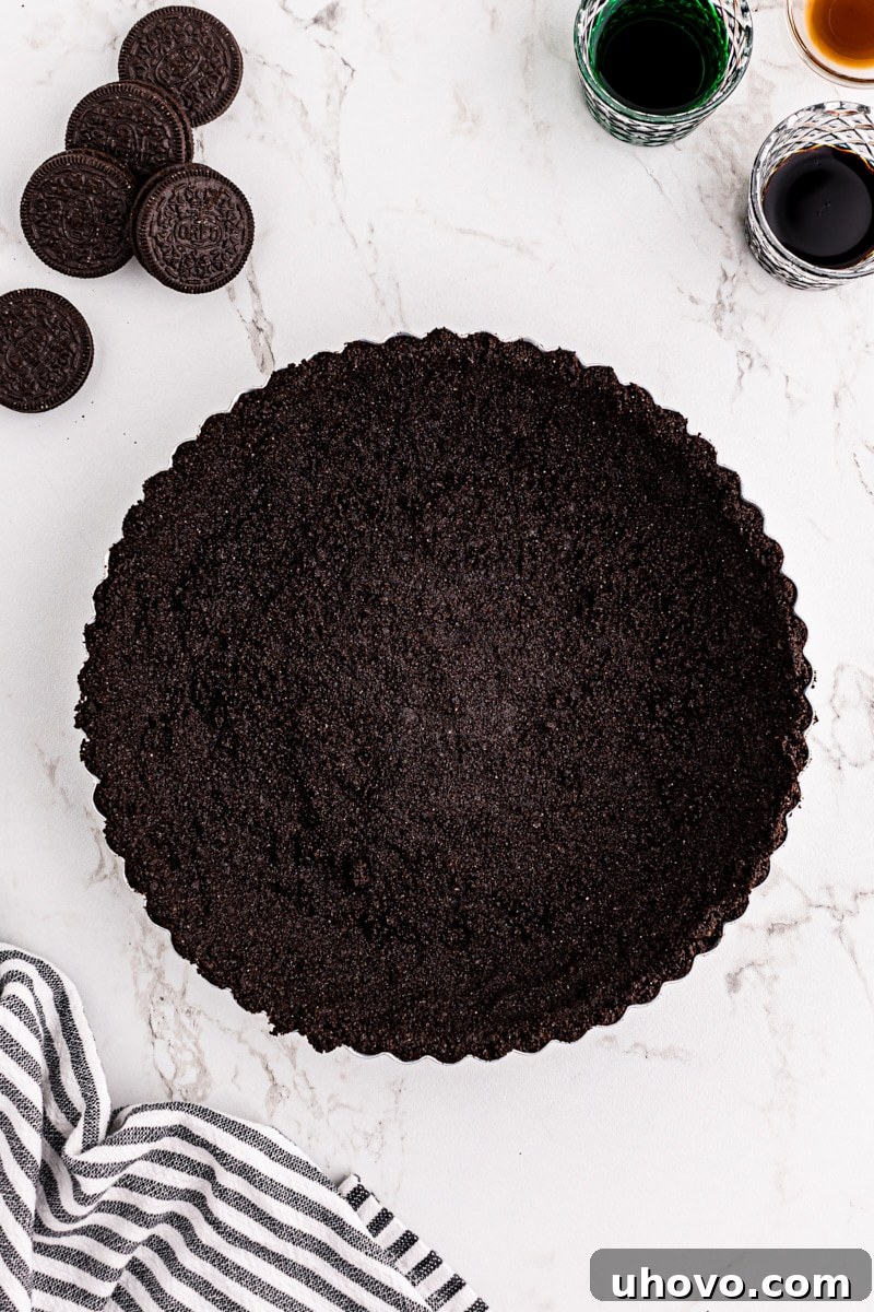 An overhead view of a perfectly formed chocolate cookie crust, pressed into a tart pan with a removable bottom, ready for baking.