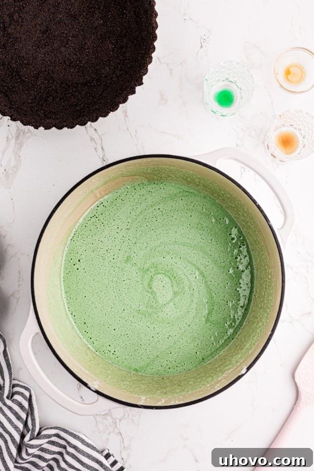 A close-up of the fully combined marshmallow mixture for Grasshopper Pie, now vibrant green and ready for chilling in a large saucepan.