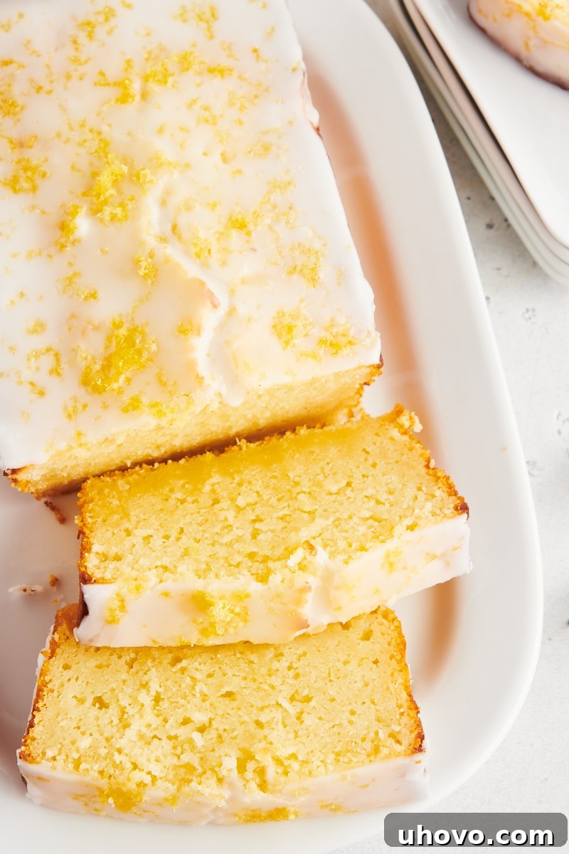 Overhead view of lemon loaf cake on platter with 2 slices cut