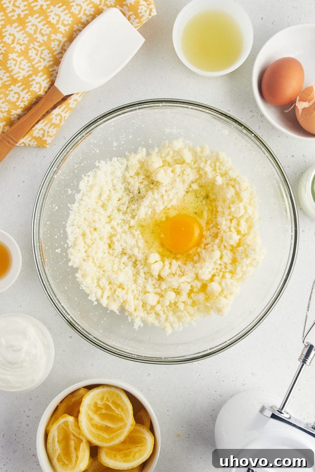 Overhead view of first egg cracked into creamed butter and sugar
