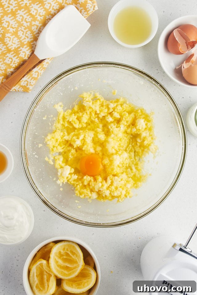 Overhead view of egg cracked into creamed butter and sugar