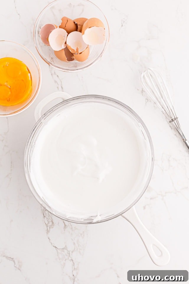 Overhead view of the egg white and sugar mixture in a double boiler, now smooth and slightly thickened after whisking constantly over heat.