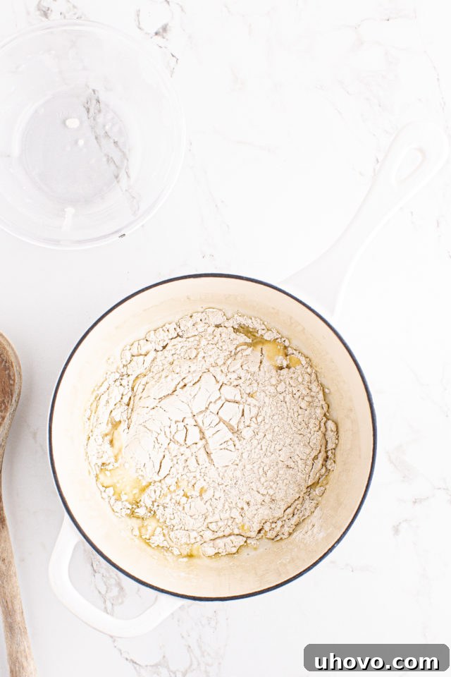 Overhead view of flour added to other choux pastry ingredients
