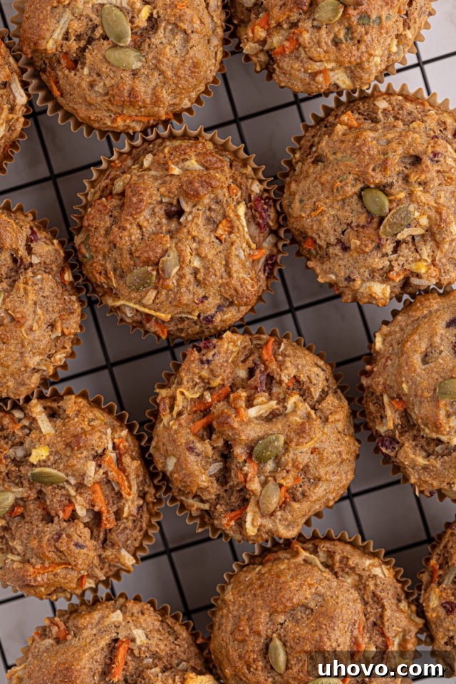 Overhead view of several Morning Glory Muffins cooling on a wire rack, steam gently rising, ready to be enjoyed.