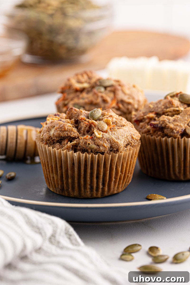 Three perfectly baked Morning Glory Muffins arranged on a rustic blue plate, highlighting their appetizing golden color and rich ingredients.