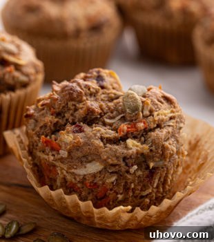A partially unwrapped morning glory muffin with more muffins in the background
