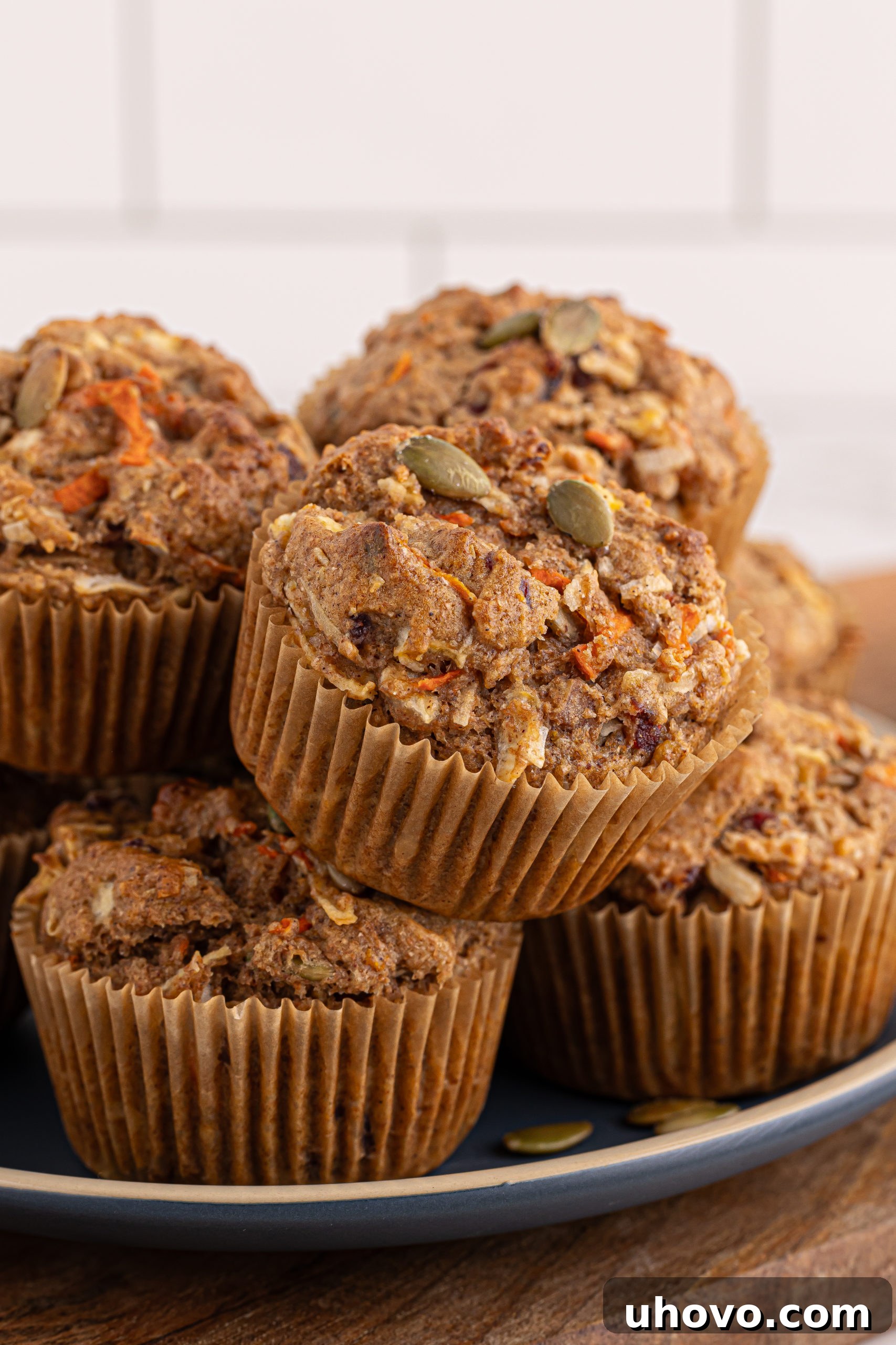 Three golden-brown Morning Glory Muffins artfully arranged on a blue ceramic plate, ready to be enjoyed.