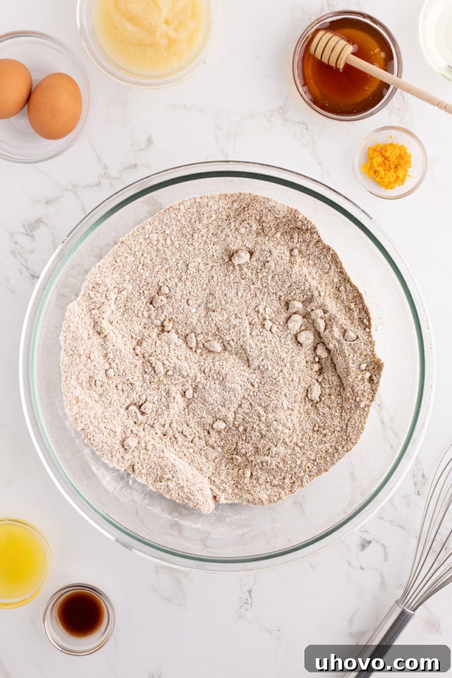 Close-up overhead view of mixed dry ingredients (flours, sugar, spices, leavening agents) for morning glory muffins, showing they are thoroughly combined.