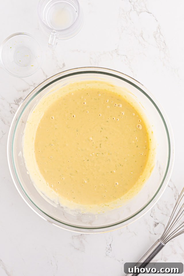 An overhead view of the fully mixed, smooth key lime pie filling in a glass mixing bowl, ready to be poured.