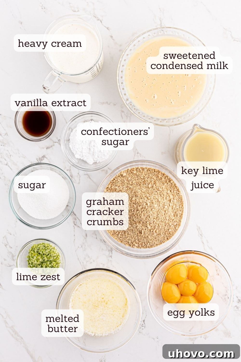 An overhead view of various ingredients for key lime pie bars, including limes, eggs, butter, and condensed milk, arranged aesthetically.