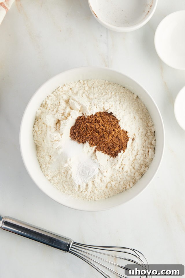 Overhead view of flour, baking powder, salt, and remaining chai spices in a mixing bowl before whisking.