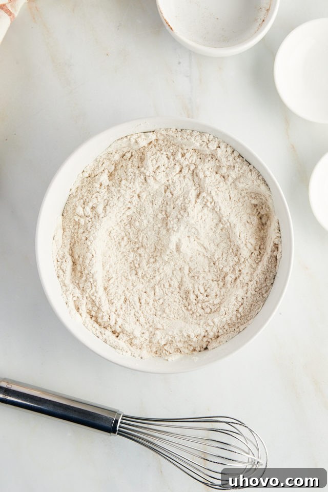 Overhead view of dry ingredients for cookies, including flour and spices, neatly whisked together in a mixing bowl.