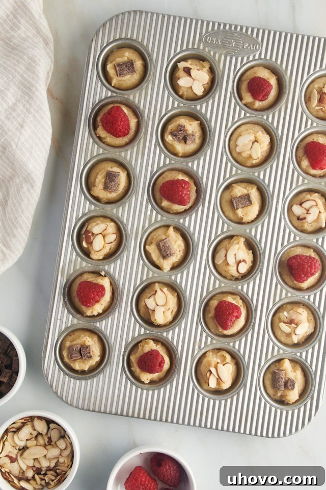 overhead view of financiers batter topped with various toppings in a mini muffin pan