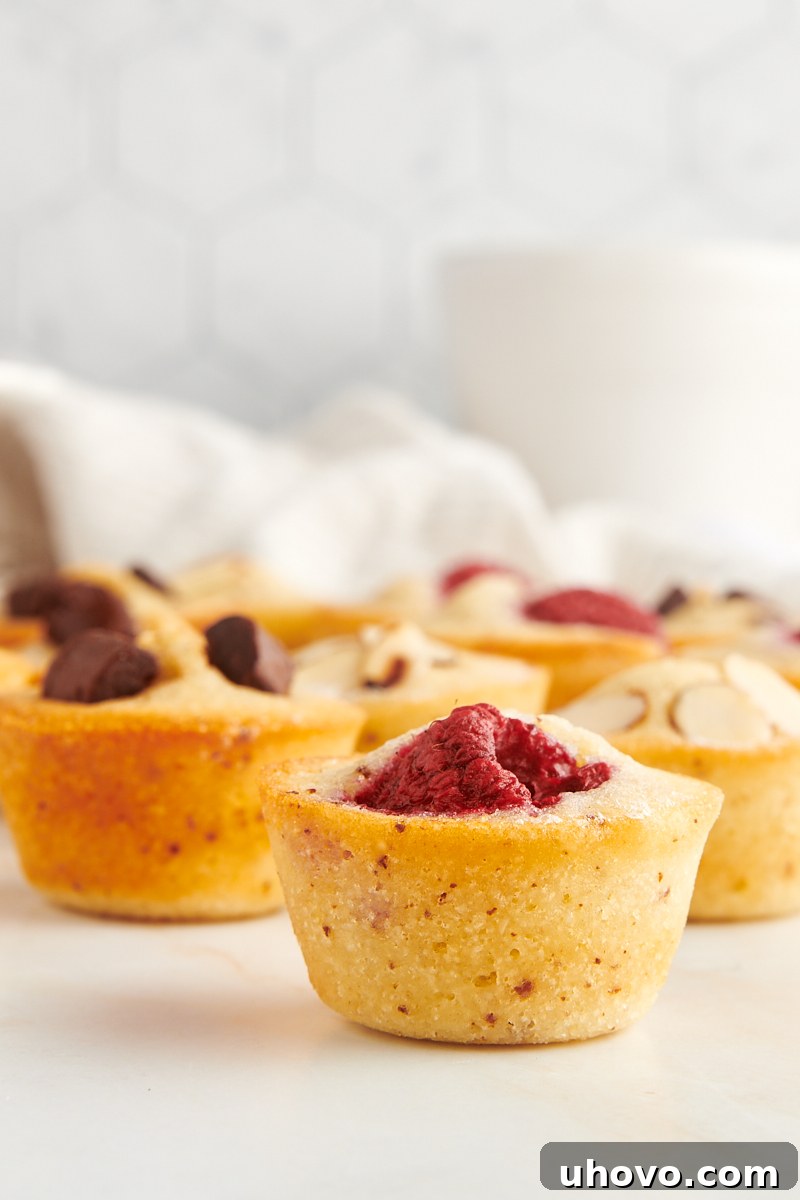 a raspberry-topped financier on a marble countertop with more financiers in the background