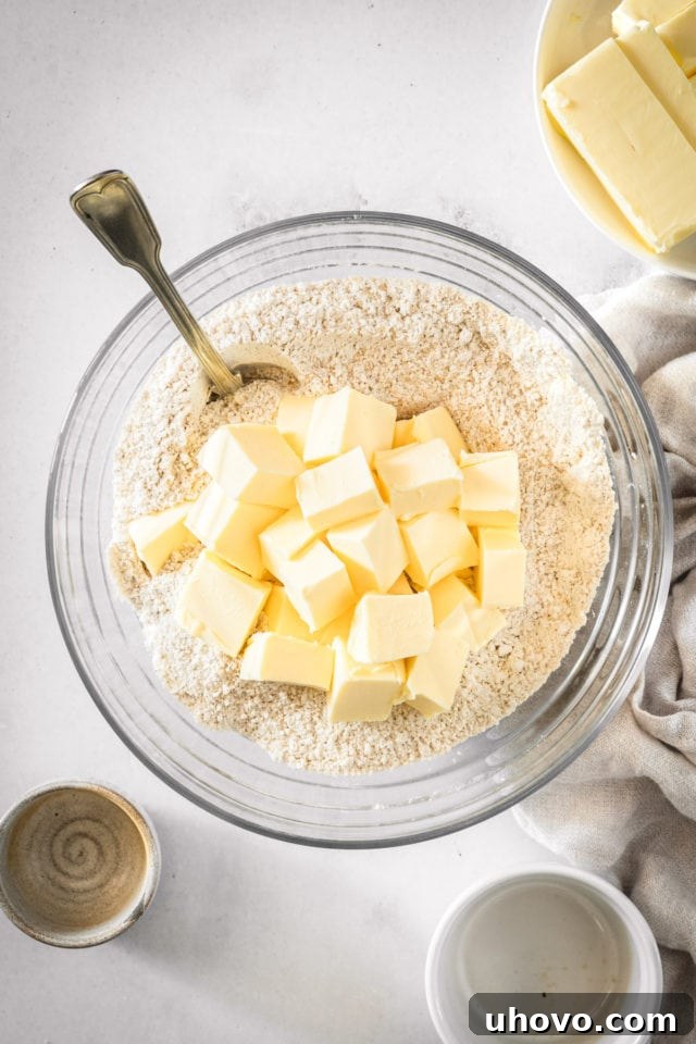 Overhead view of softened butter being added to the dry ingredients for the crumb mixture, ready to be blended.