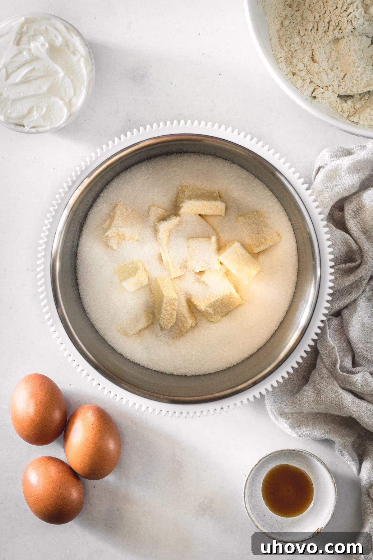Overhead view of softened butter and granulated sugar creaming together in a mixing bowl, becoming light and fluffy.