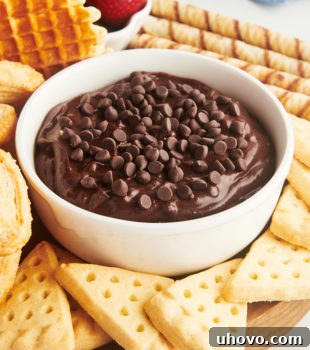 A bowl of brownie batter dip surrounded by various dippers on a wooden board
