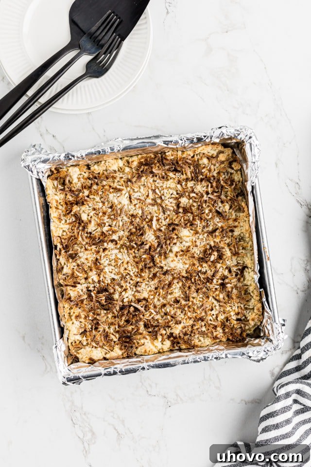 Overhead view of black bottom coconut bars baking in the pan, golden brown and bubbling