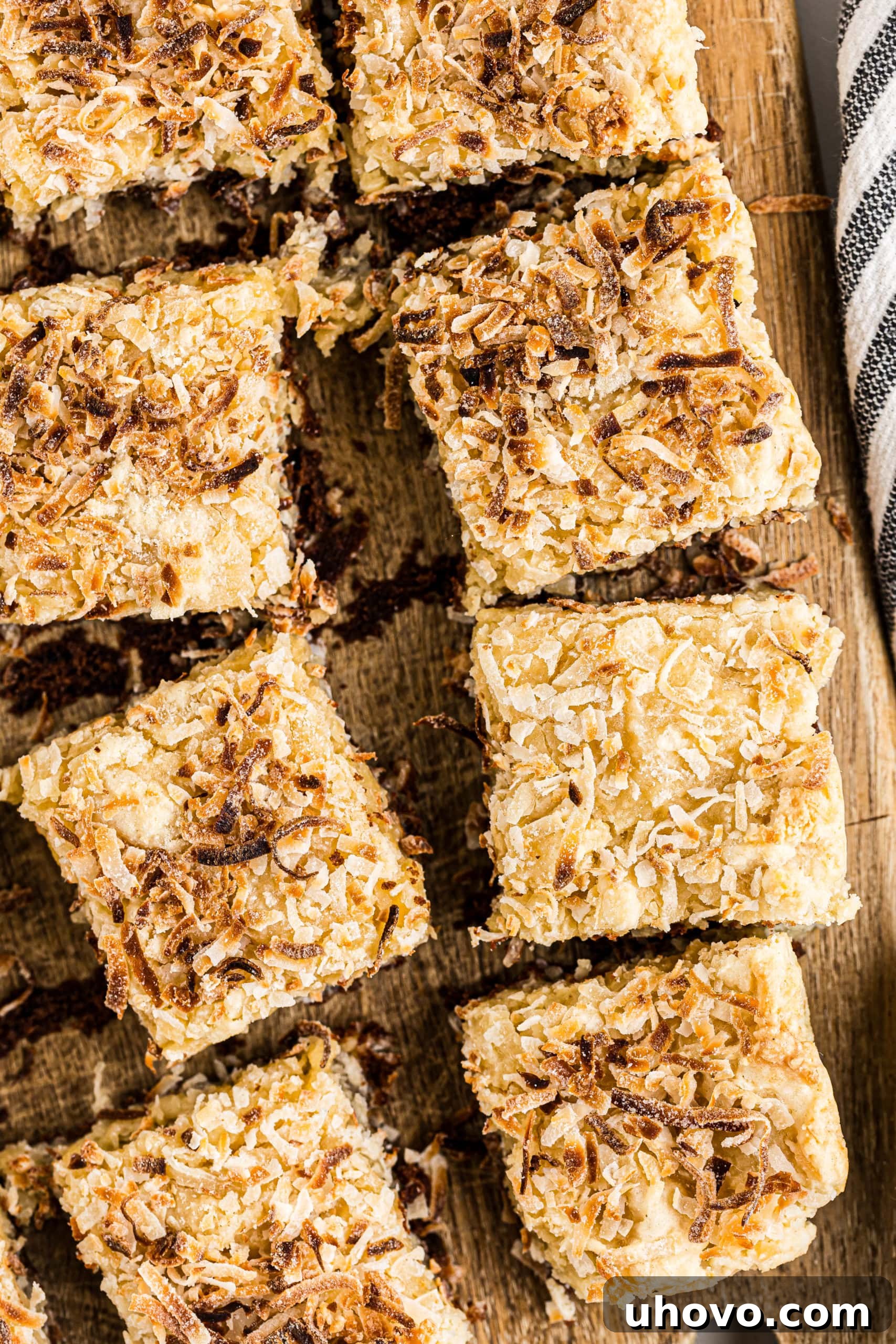 Overhead view of several Black-Bottom Coconut Bars neatly arranged on a wooden cutting board