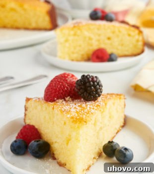 a slice of lemon ricotta cake served with fresh berries on a white plate
