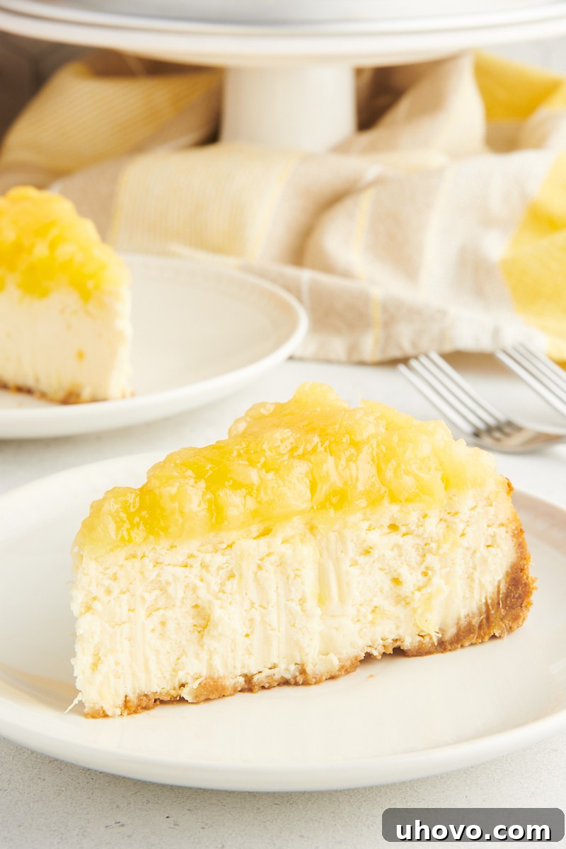 A perfectly sliced pineapple cheesecake, revealing its creamy layers and a generous pineapple topping, resting on a pristine white plate, inviting a taste of its tropical decadence.