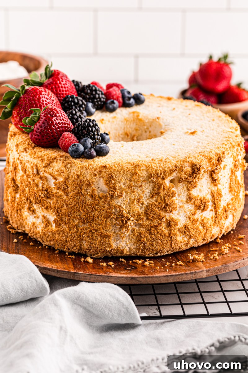 A stunning Angel Food Cake topped with vibrant fresh berries, served on a rustic wooden tray, showcasing its elegant simplicity.