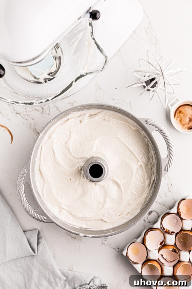 Angel food cake batter spread evenly in a tube pan, ready for baking.