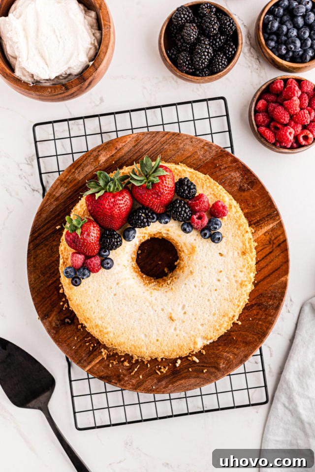 A beautifully garnished Angel Food Cake, adorned with an assortment of fresh berries, ready for serving.