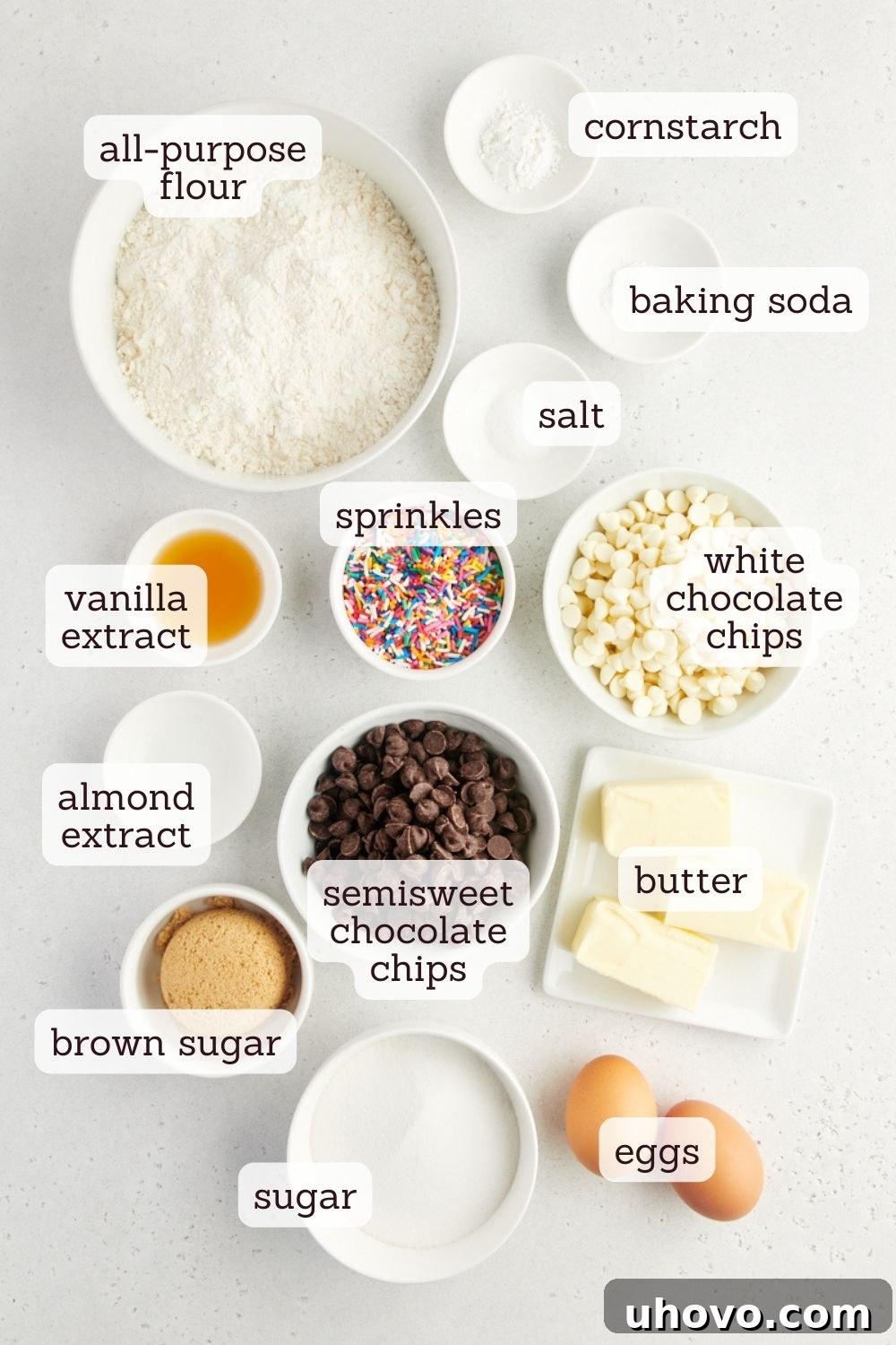 An inviting overhead shot showcasing all the essential ingredients laid out meticulously for baking soft and chewy sprinkle chocolate chip cookies, including flour, sugars, butter, eggs, chocolate chips, and colorful jimmie sprinkles, all ready for preparation.