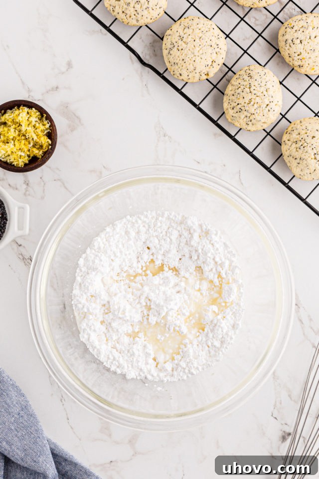 Overhead view of confectioners' sugar and fresh lemon juice being stirred together in a glass mixing bowl to form the glaze.