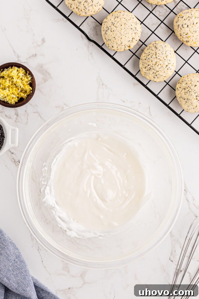 Overhead view of a perfectly smooth, drizzling lemon glaze in a glass mixing bowl, ready for application.