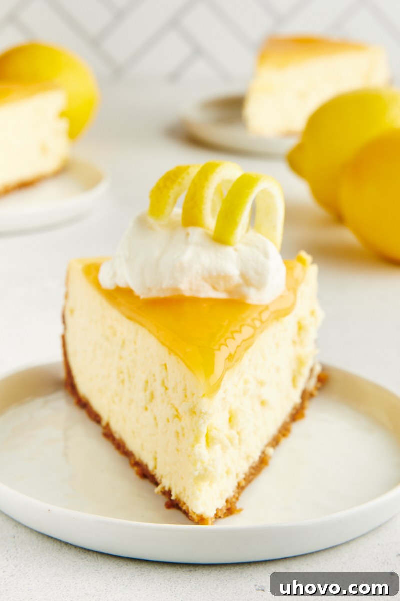 A perfectly sliced lemon cheesecake on a white plate, garnished with a lemon twist.