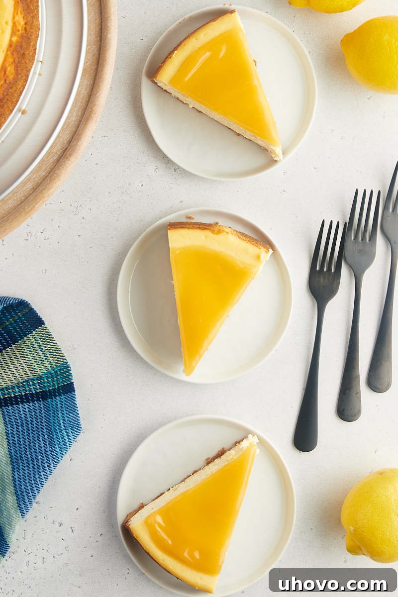 Overhead view of three perfectly cut slices of lemon cheesecake, each on a pristine white plate.