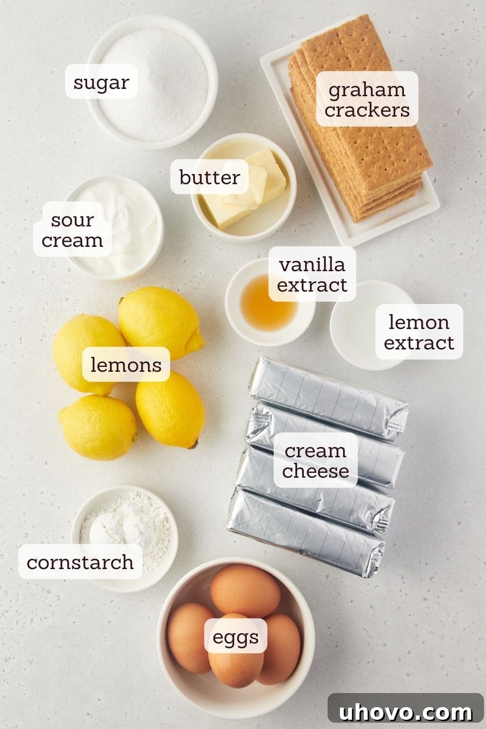 Overhead view of various ingredients for lemon cheesecake, including lemons, cream cheese, and graham crackers.