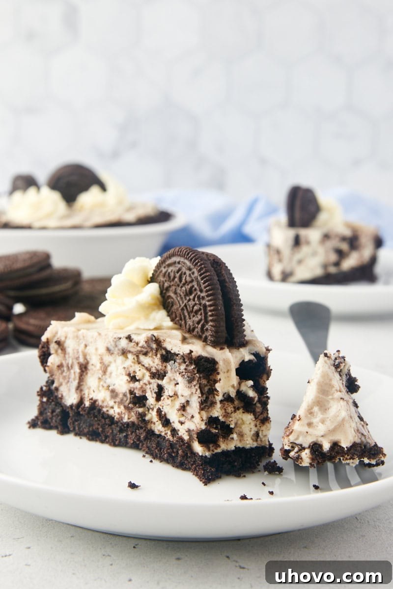 A delectable slice of No-Bake Oreo Pie on a pristine white plate, with a fork poised for a bite, showcasing its creamy filling and cookie crust.