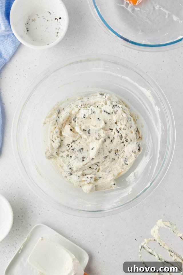 Overhead view of the fully mixed Oreo pie filling in a glass mixing bowl, showcasing its creamy texture with visible cookie chunks.