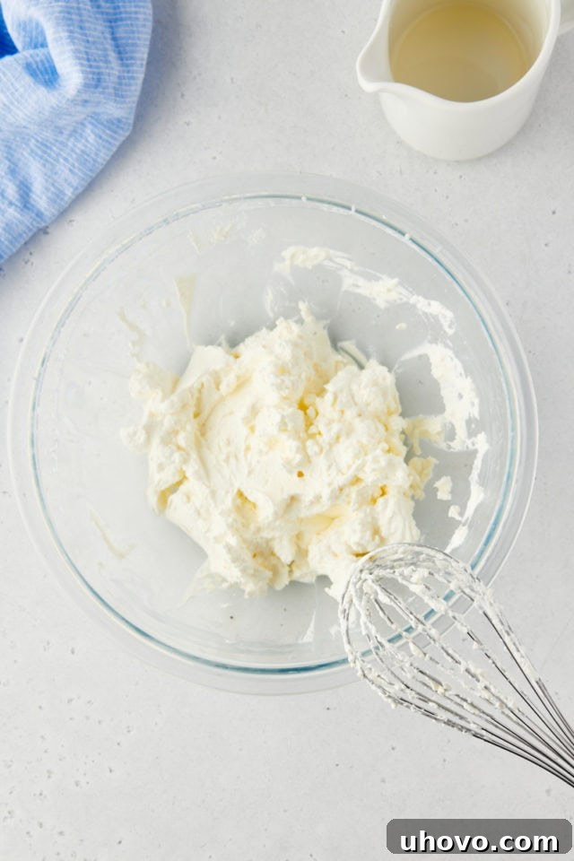 Overhead view of heavy cream whipped to perfect stiff peaks in a clear glass mixing bowl, showing its airy and stable texture.