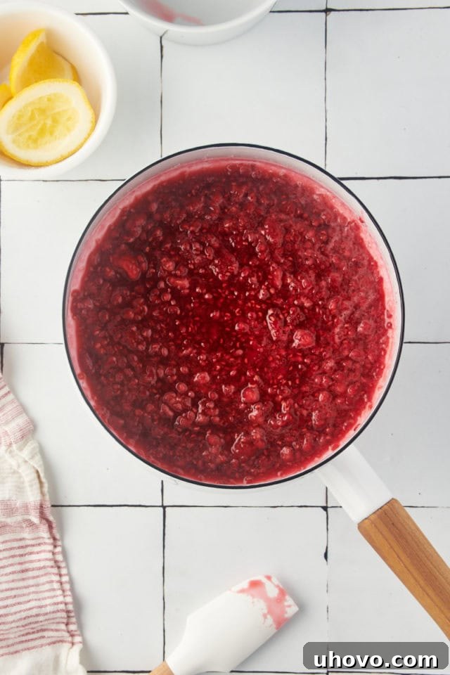 Overhead view of raspberry mixture after being cooked down, appearing saucy and softened, before blending.