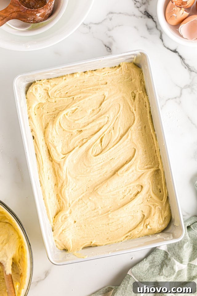 Overhead view of the first layer of coffee cake batter evenly spread in a metal baking pan.