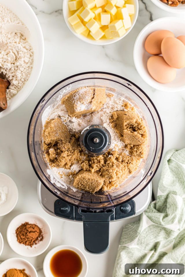 Overhead view of brown sugar and flour combined in a food processor, starting the crumb topping preparation.