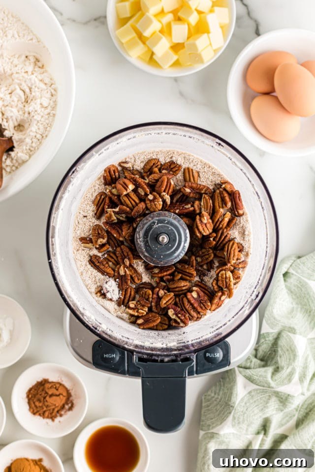 Overhead view of pecans being added to the brown sugar and flour mixture in a food processor for the crumb topping.