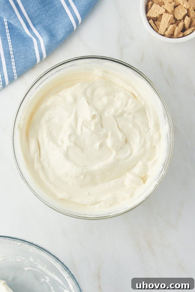 The fully combined cream cheese and whipped cream mixture, creating a light and airy no-churn ice cream base in a glass mixing bowl.